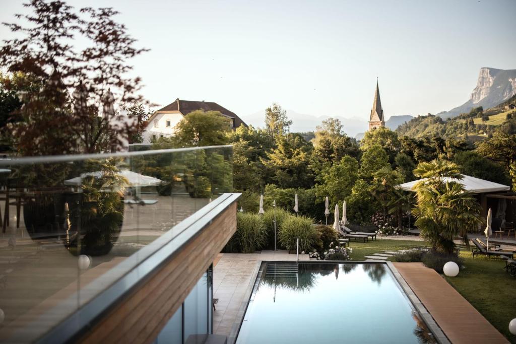ein Haus mit einem Pool und einem Garten in der Unterkunft ALPIANA - green luxury Dolce Vita Hotel in Völlan