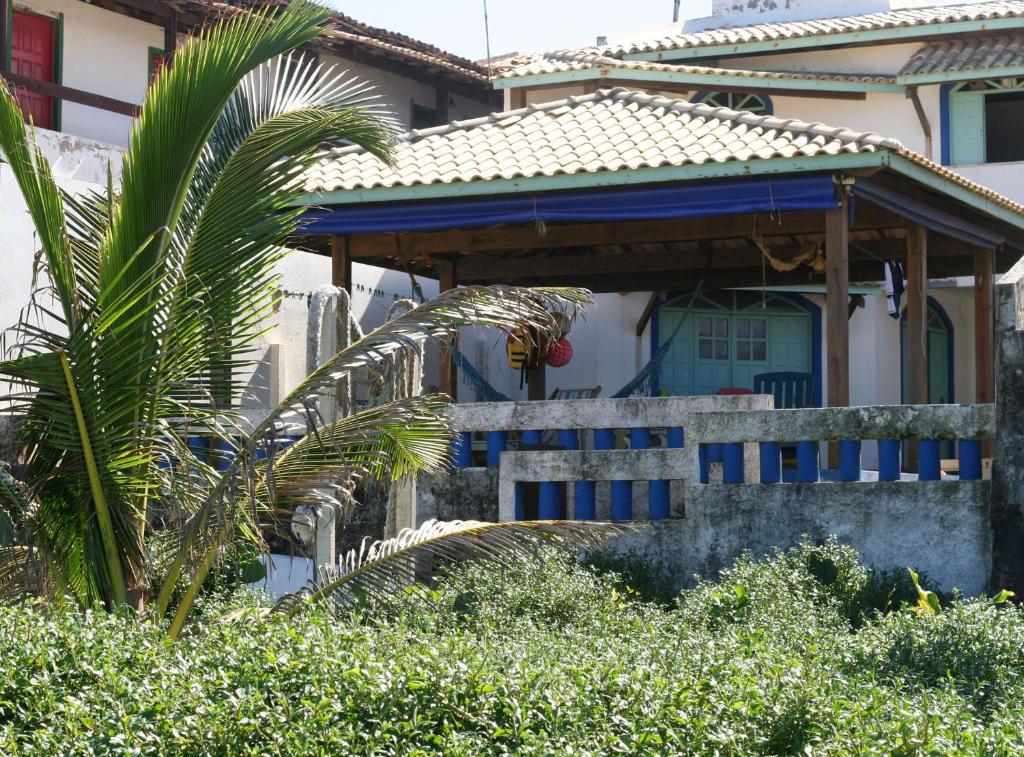 a house with a blue porch and a palm tree at Alfazema Cultural Bed and Breakfast in Arembepe