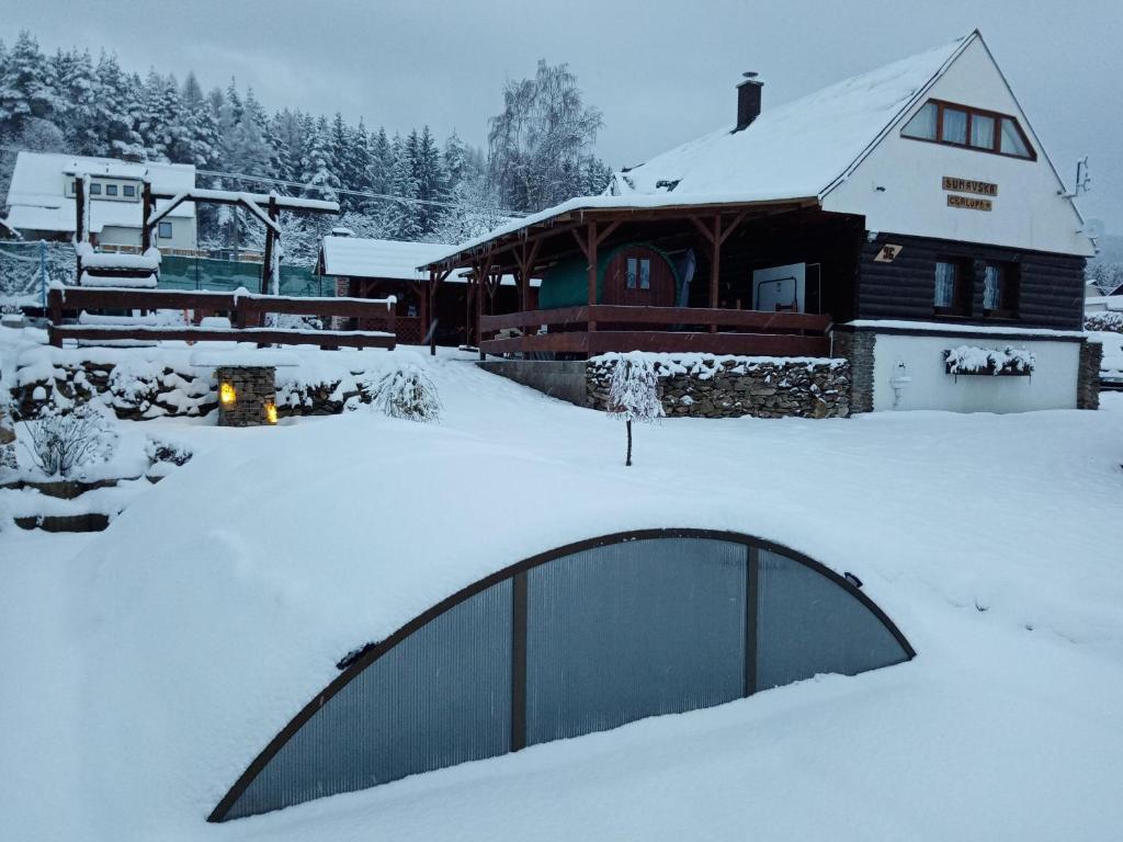 einen schneebedeckten Hof mit einem Haus und einem Gebäude in der Unterkunft Šumavská rekreační chalupa in Pohorsko