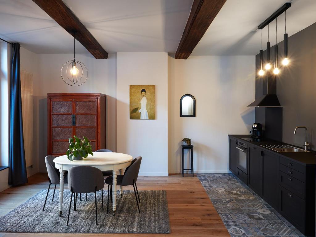 une cuisine et une salle à manger avec une table et des chaises dans l'établissement La Petite Histoire gîtes-appartements, à Ath