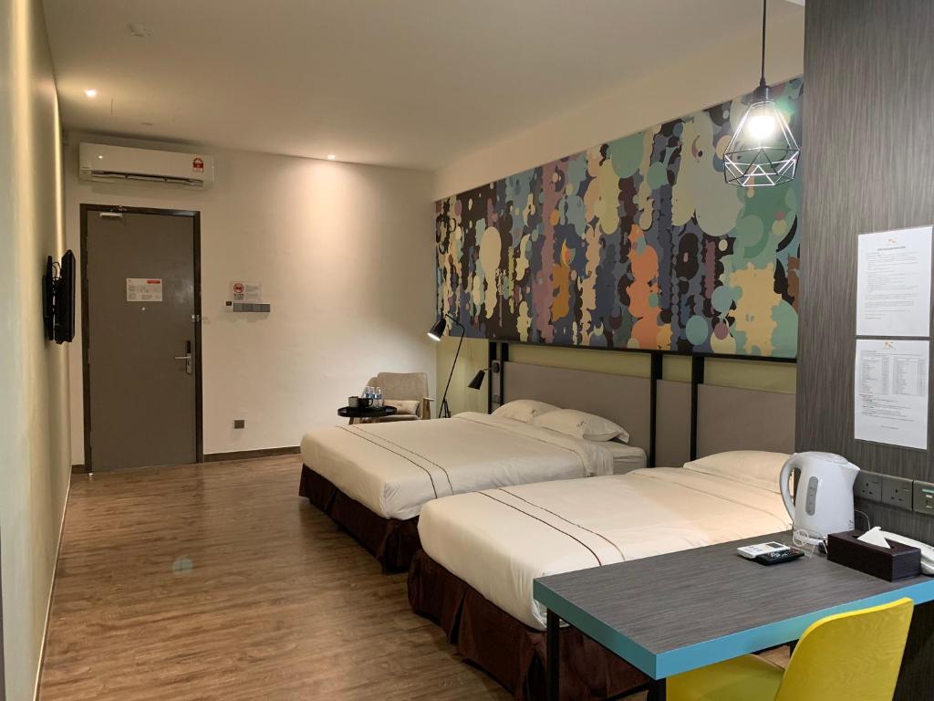 ein Hotelzimmer mit 2 Betten und einem Tisch in der Unterkunft K Hotel in Kota Kinabalu