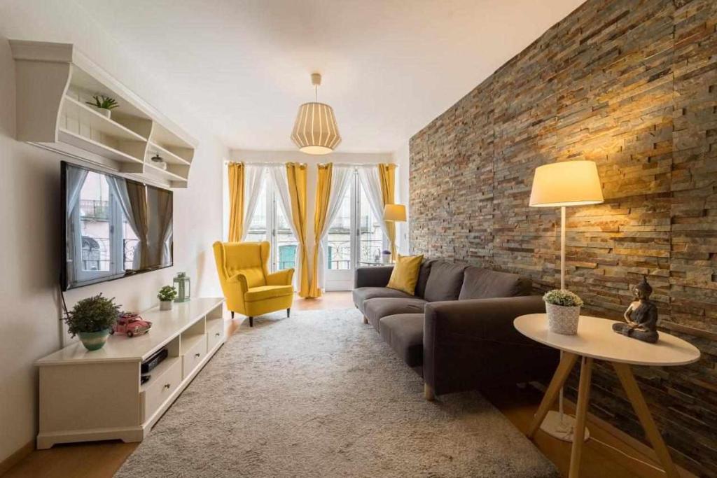 Sé Guesthouse في براغا: غرفة معيشة مع أريكة وجدار من الطوب