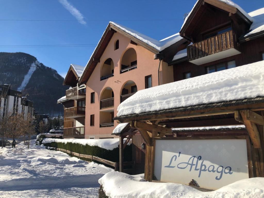 ein schneebedecktes Gebäude mit einem Schild davor in der Unterkunft Le Refuge de L'alpaga Superbe duplex au pied des pistes avec Parking couvert gratuit in La Salle Les Alpes