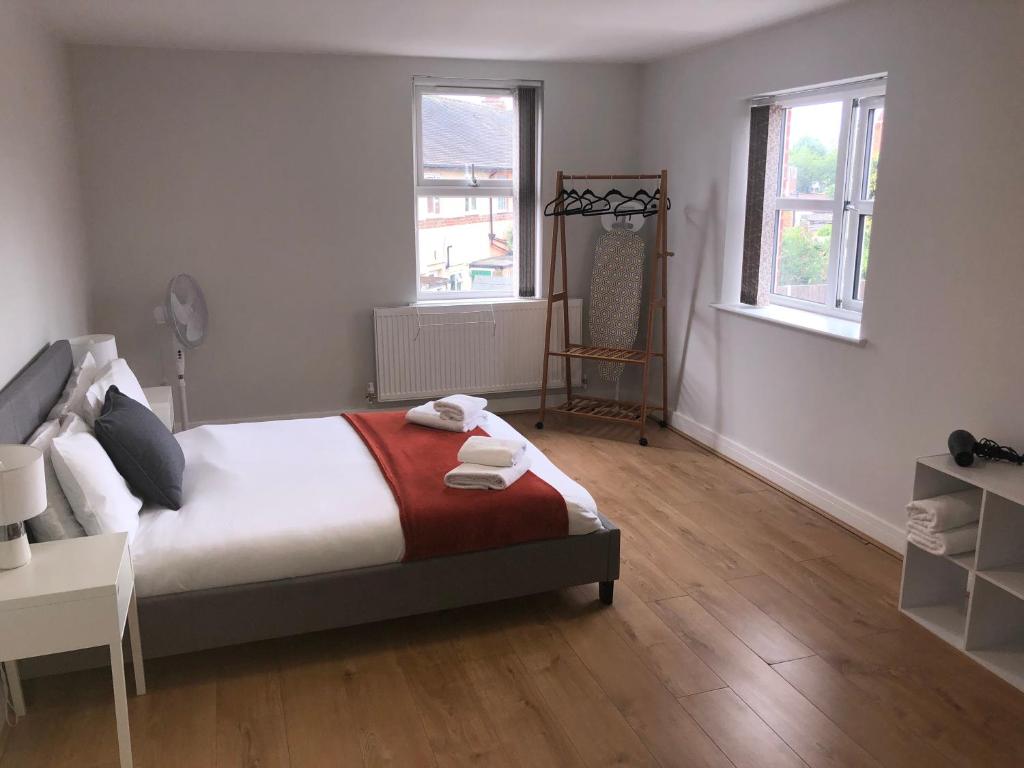 a bedroom with a bed and two windows at 2 Bedroom Large First Floor Apartment with FREE Parking in Loughborough