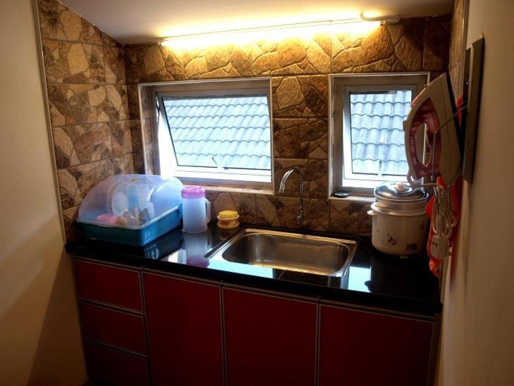 a kitchen counter with a sink and two windows at Fang Zu Ming Concept Guesthouse in Ayer Itam