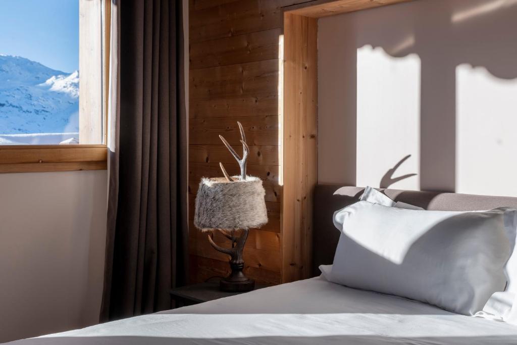 a bedroom with a bed and a window at Chalet Hotel Kaya in Les Menuires