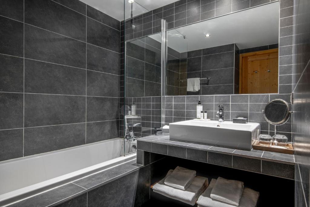 a bathroom with a sink and a mirror at Chalet Hotel Kaya in Les Menuires