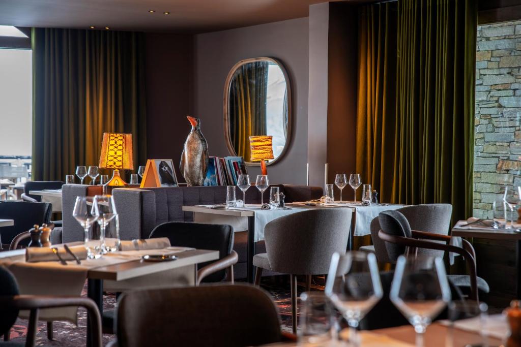 a restaurant with tables and chairs with wine glasses at Chalet Hotel Kaya in Les Menuires