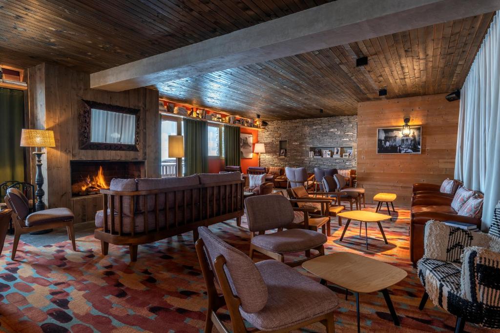 a lobby with couches and chairs and a fireplace at Chalet Hotel Kaya in Les Menuires
