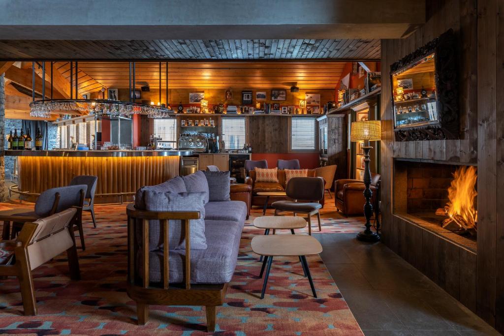 a bar with a couch and chairs and a fireplace at Chalet Hotel Kaya in Les Menuires