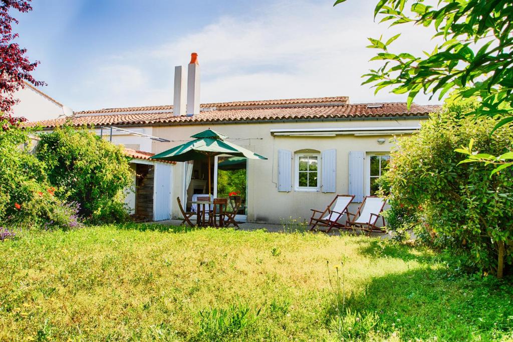 una piccola casa bianca con sedie e portico di Charmante maison au coeur de Saint Martin a Saint-Martin-de-Ré