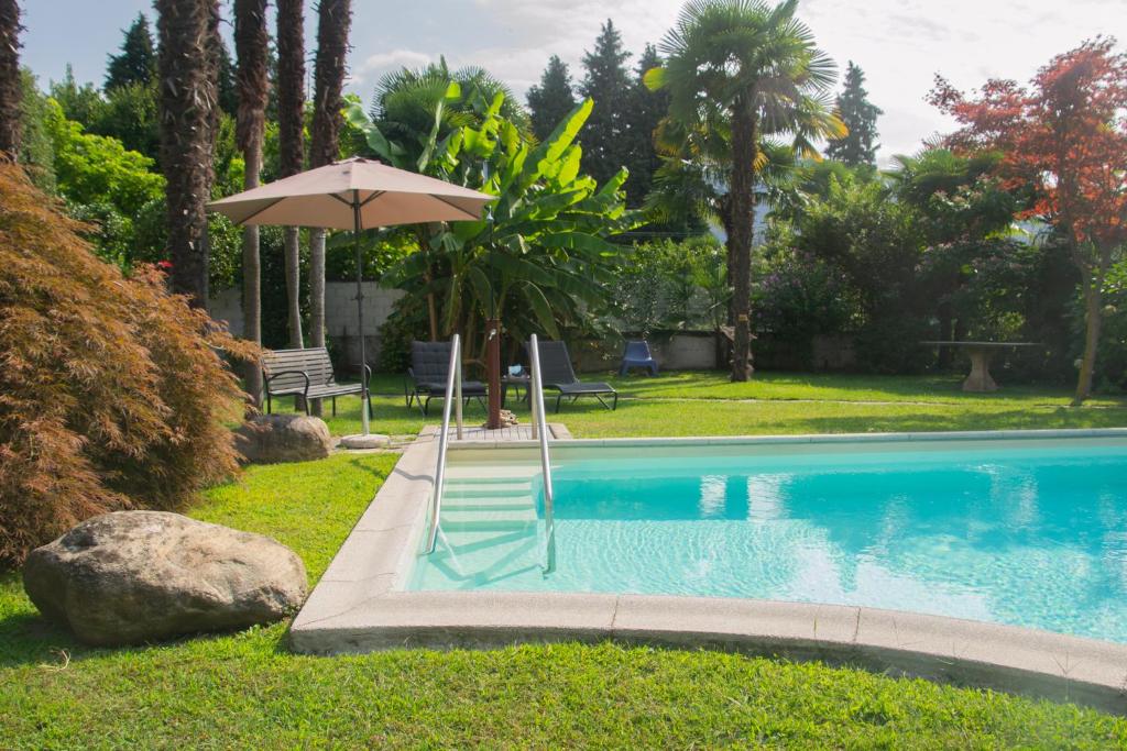 uma piscina com guarda-sol e cadeiras em Villa Michelangelo - WelcHome em Cannobio