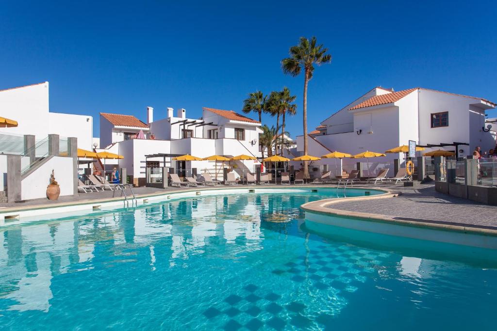 a swimming pool in front of some white buildings at Apartamentos Villa Florida in Caleta De Fuste