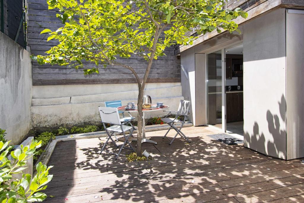 un patio avec une table et des chaises sous un arbre dans l'établissement Moutte, à Saint-Cyr-sur-Mer