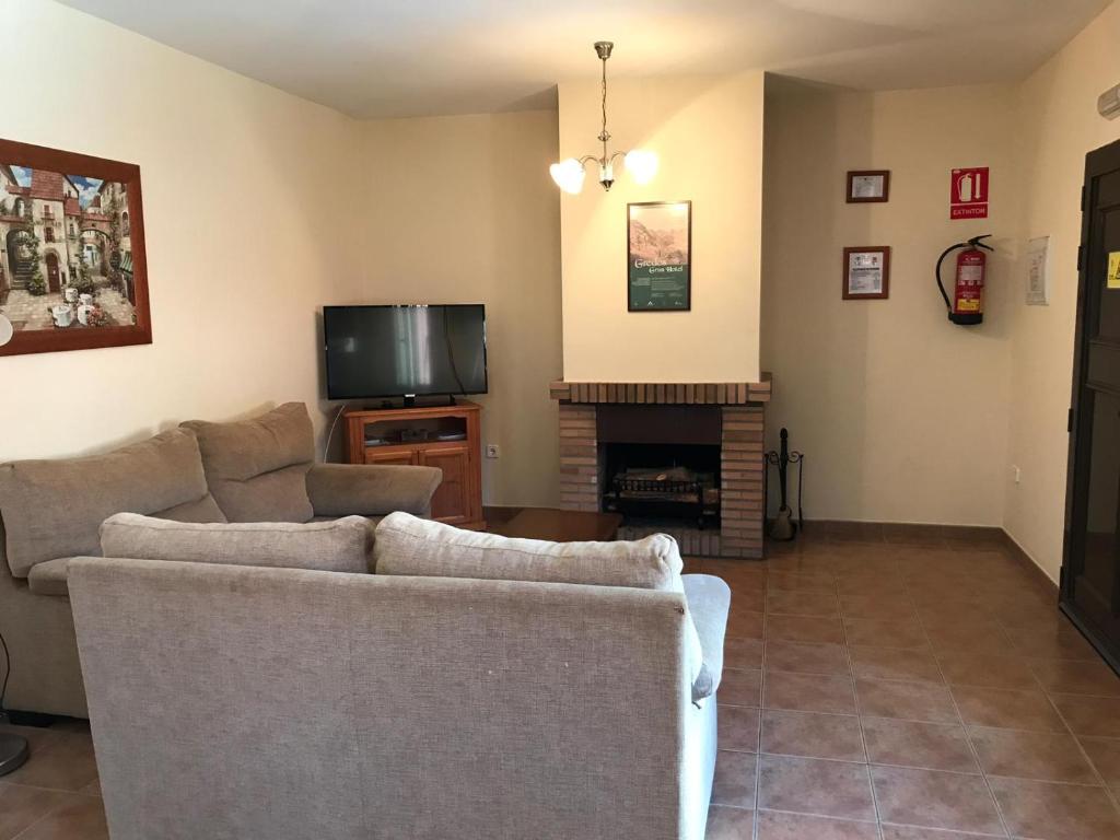 ein Wohnzimmer mit 2 Sofas und einem TV in der Unterkunft Casa Rural las Escuelas II in El Hoyo de Pinares