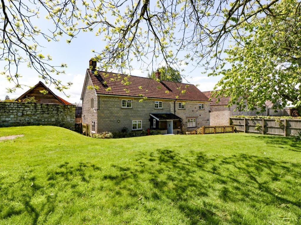 an old stone house with a fence and a yard at The Stable House in Sherborne