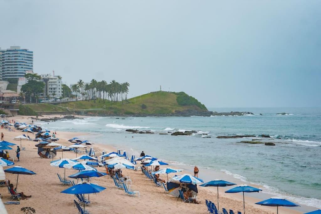 a beach with many blue umbrellas and people on it at Apartamento Incrível in Salvador