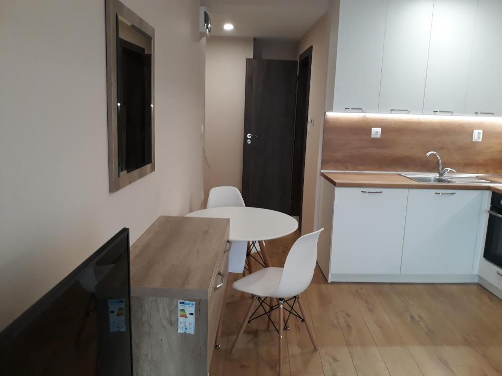 uma pequena cozinha com uma mesa e cadeiras brancas em Studio 16A Vasil Aprilov 64 - Plovdiv em Plovdiv