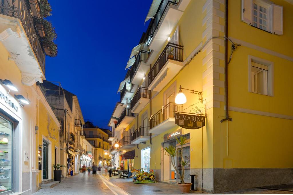 una calle de la ciudad por la noche con edificios amarillos en Hotel La Marina, en Santa Maria di Castellabate