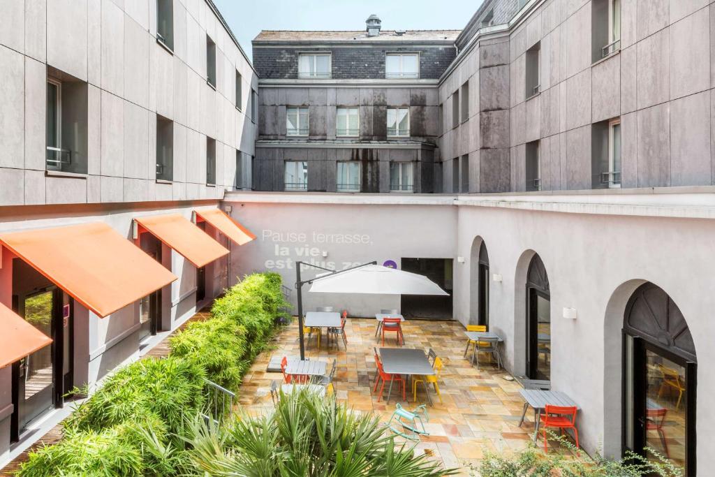 um pátio interno de um edifício com mesas e cadeiras em Best Western Hotel San Benedetto em Cholet