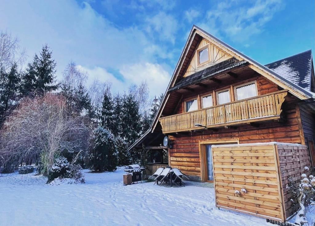 a log cabin with a deck in the snow at Chata Leona in Gorlice