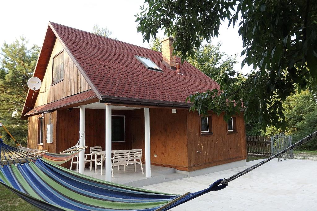 una casa con una hamaca delante en Godzisz - domek rekreacyjny, en Sobolew