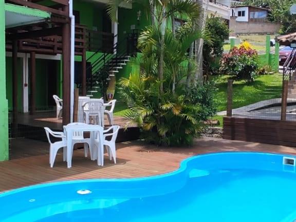 un patio con mesa y sillas junto a una piscina en Ferrugem Pousada Região, en Garopaba
