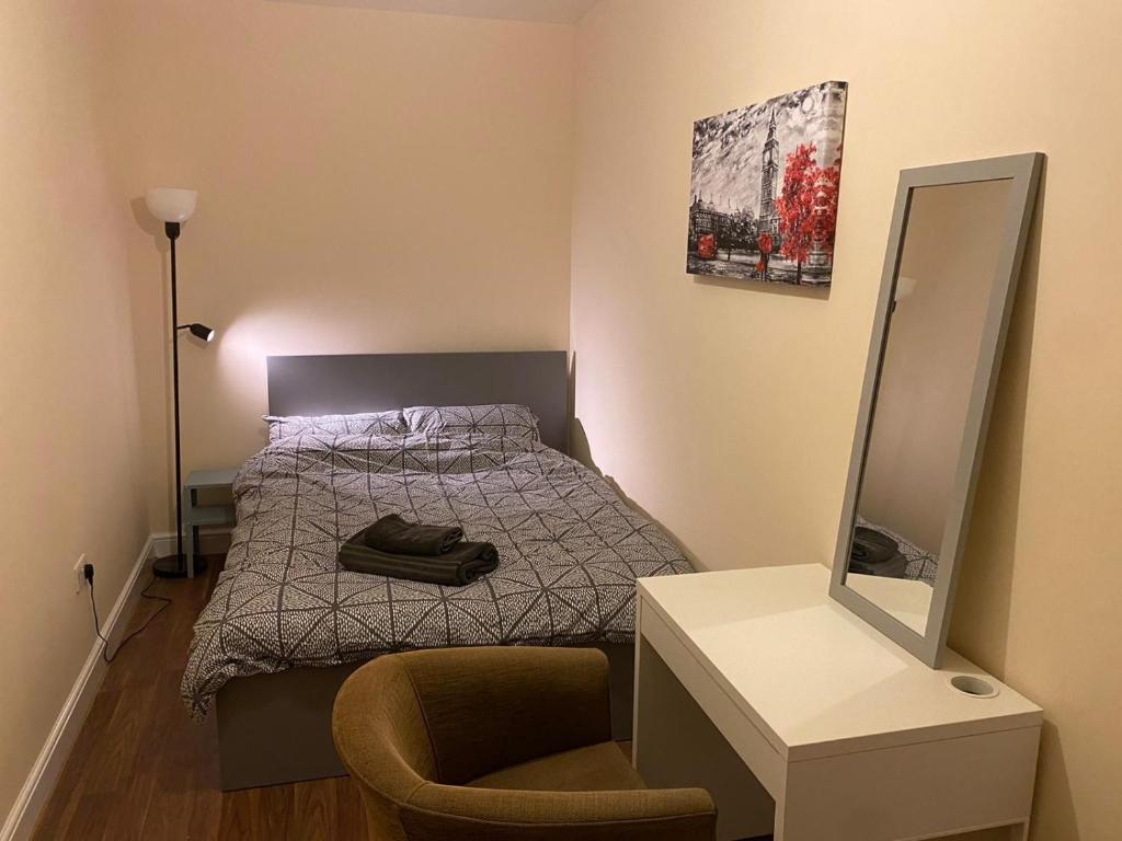 Cosy Ealing Homestay في لندن: غرفة نوم صغيرة مع سرير ومرآة