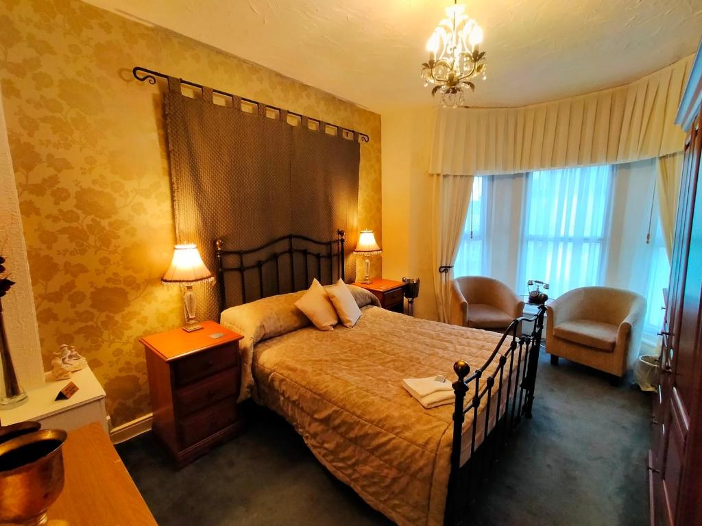 um quarto com uma cama, uma cadeira e uma janela em Hotel Babylon em Blackpool