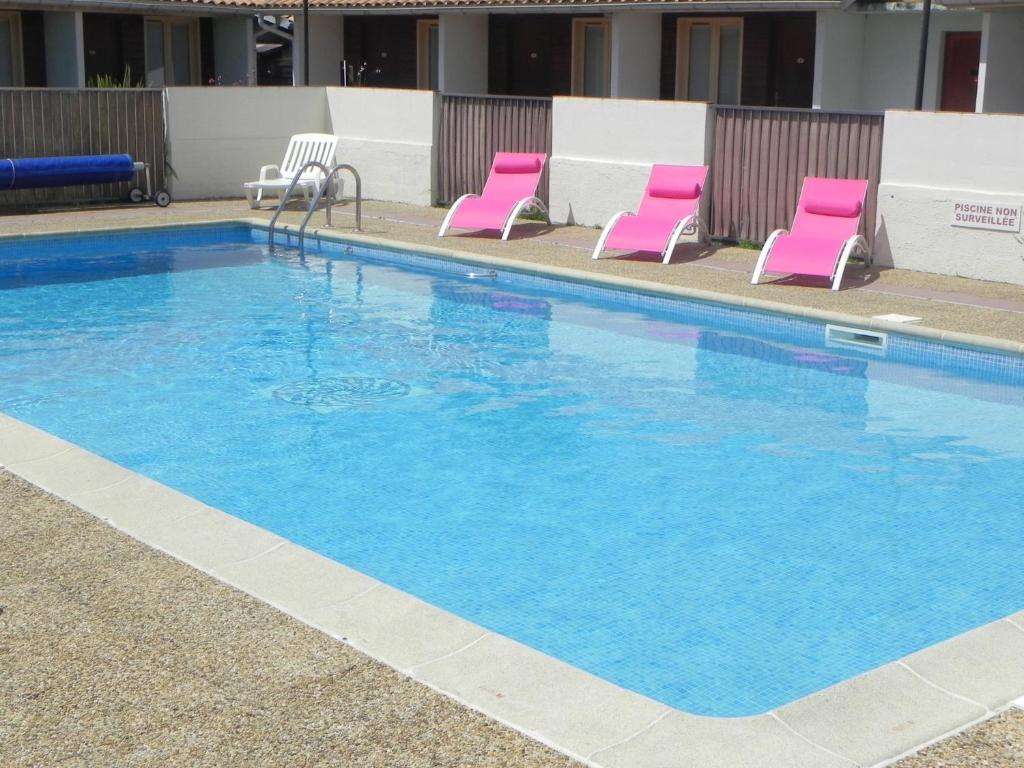 a large swimming pool with pink chairs in a hotel at Hotel Les Pins in Hourtin