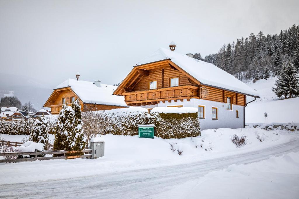 ein Holzhaus im Schnee mit einer Straße in der Unterkunft Sonnenchalet 1 im Salzburger Lungau in Mariapfarr