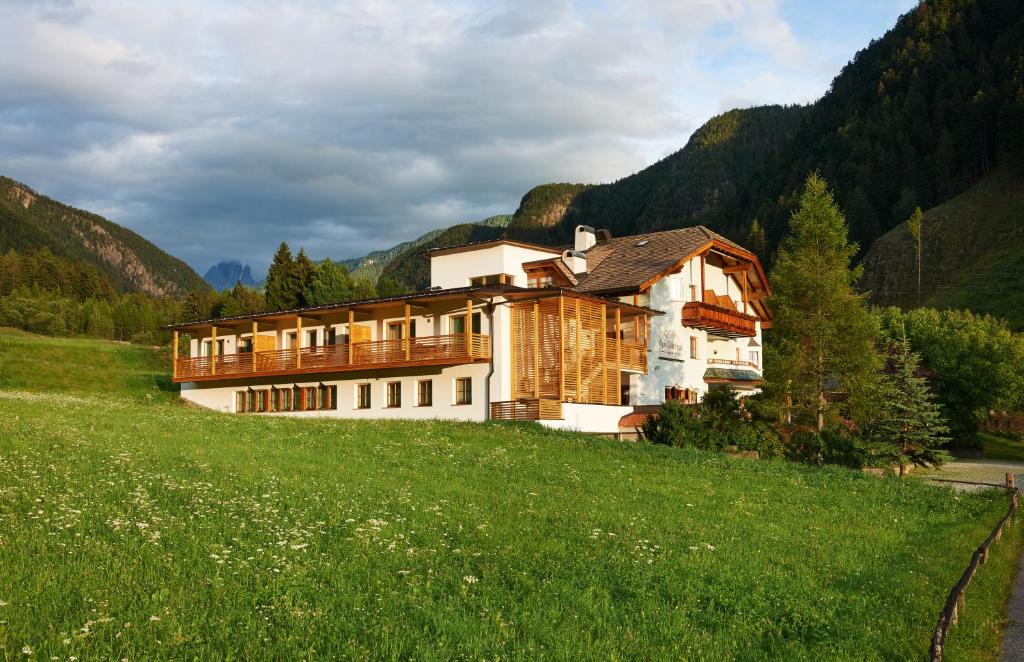 a house on a hill in a green field at Alpin Stile Hotel in Laion