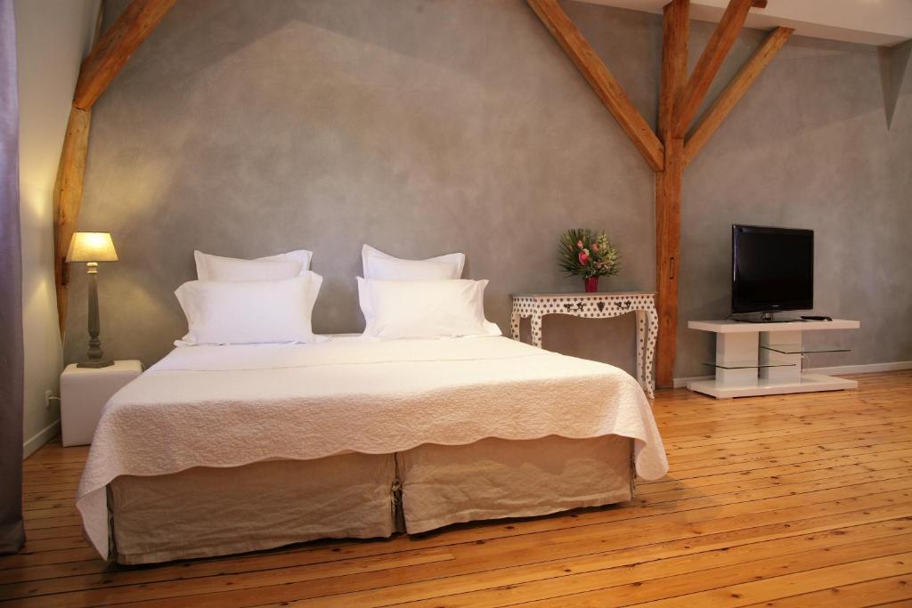 een slaapkamer met een bed met witte lakens en een televisie bij A la Fleur de Lys in Langeais