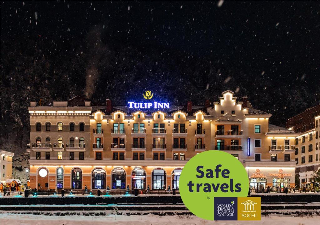 a large building with a sign on the side of it at Tulip Inn Rosa Khutor Hotel in Estosadok