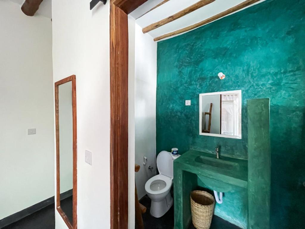 a green bathroom with a toilet and a sink at Nakupenda paje villa in Paje