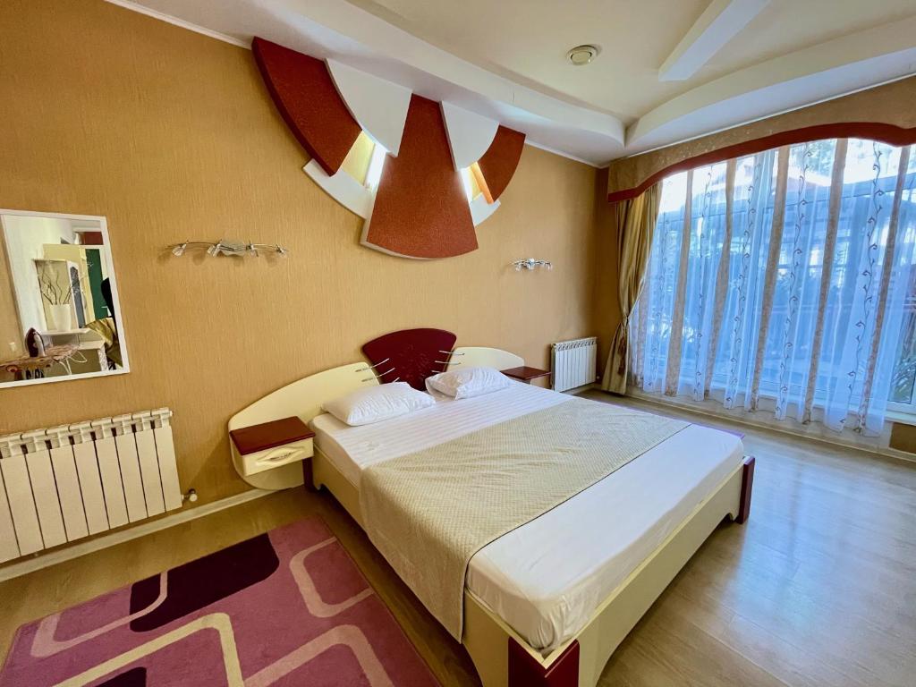ein Schlafzimmer mit einem großen Bett und einem großen Fenster in der Unterkunft Moskvа Hotel in Aluschta