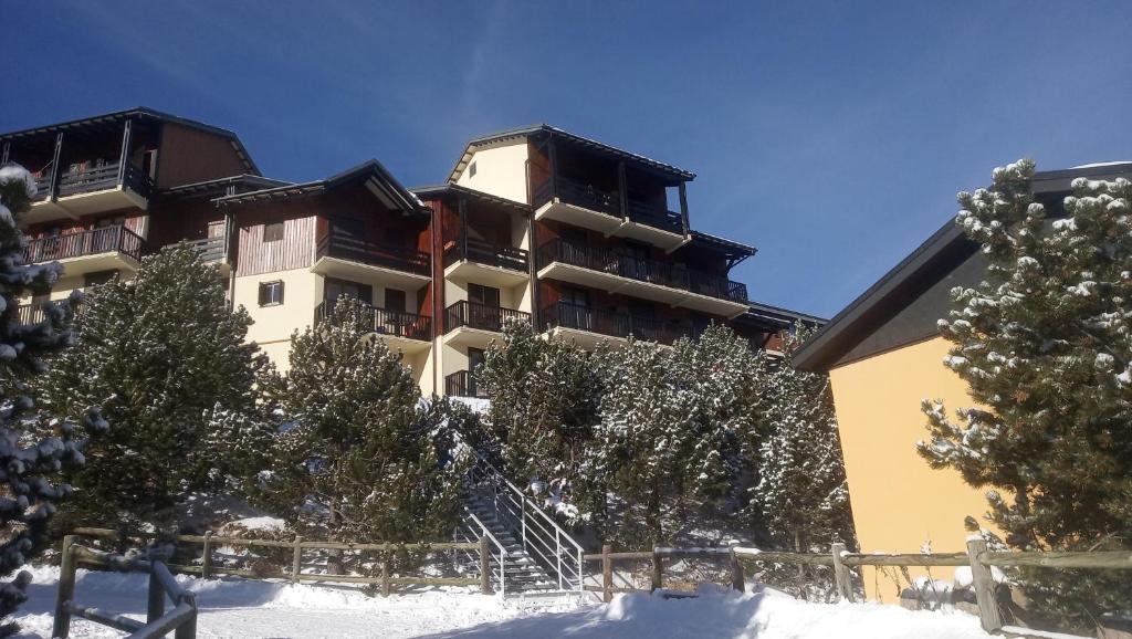 un bâtiment dans la neige avec des arbres devant dans l'établissement Bolquere P2000 by Marie&Rafael, à Bolquère-Pyrénées 2000