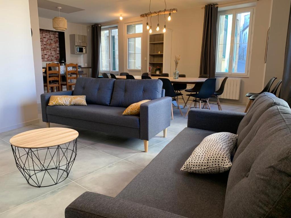 ein Wohnzimmer mit einem blauen Sofa und einem Tisch in der Unterkunft Un Toit Pour Vous in Les Épesses