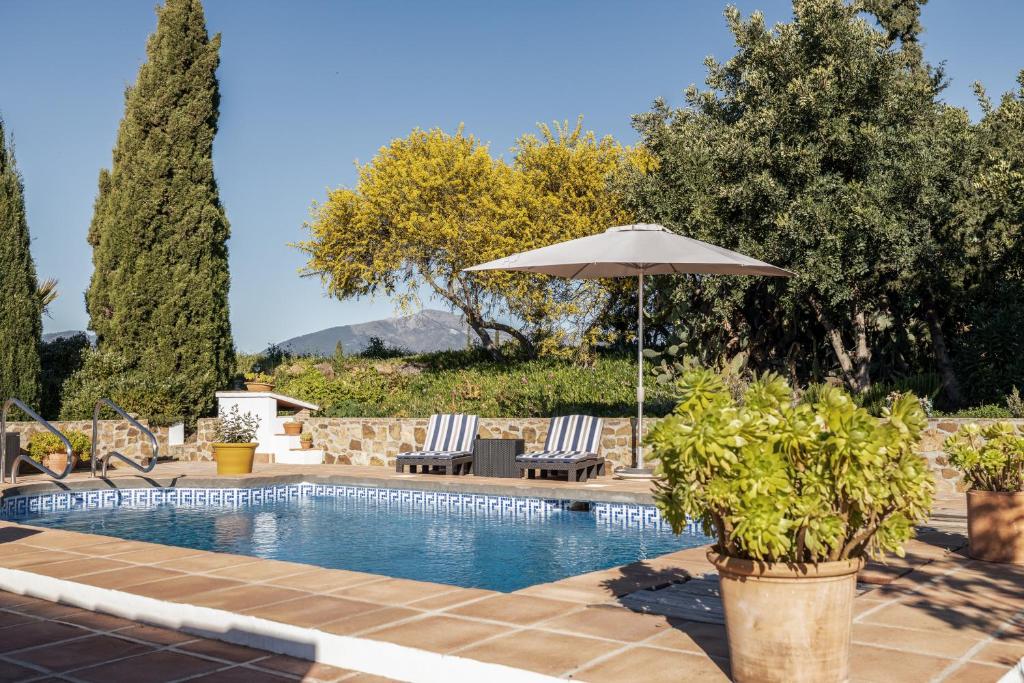 - une piscine avec 2 chaises et un parasol dans l'établissement Casa Chica, à Pizarra