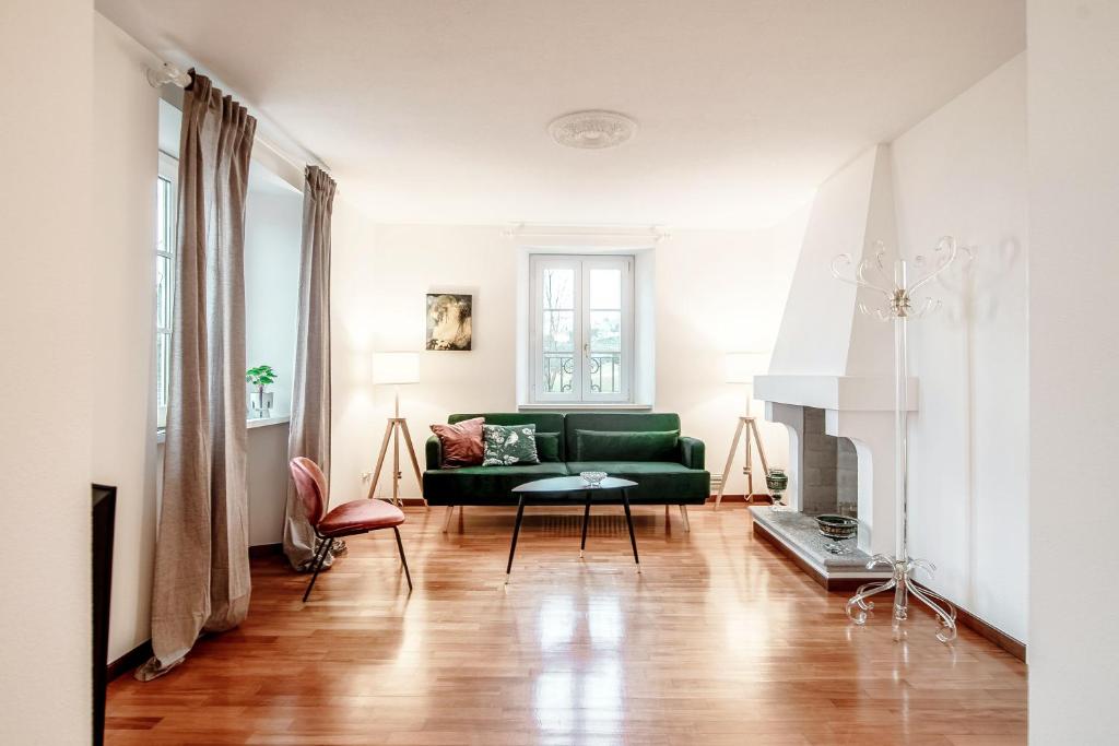 a living room with a green couch and a fireplace at Salorino Apartments by Quokka 360 - Quiet Escape with Panoramic Nature Views in Mendrisio