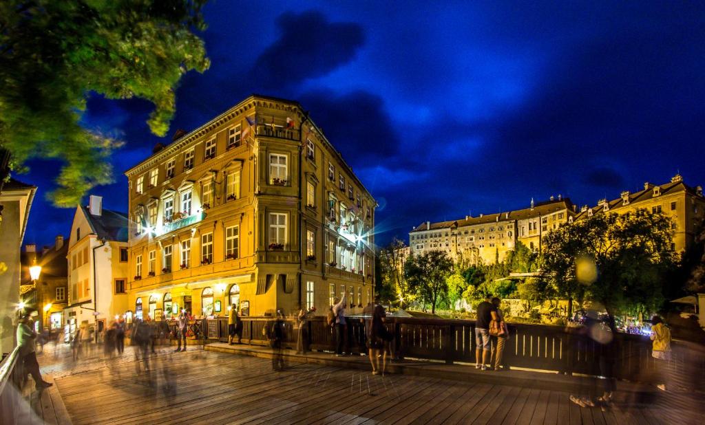 un grupo de personas caminando por una calle de la ciudad por la noche en Hotel Dvorak Cesky Krumlov en Český Krumlov
