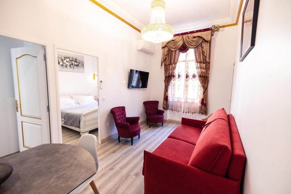 a living room with a red couch and a bed at Appartement Maison de L'Église du Couvent in Narbonne