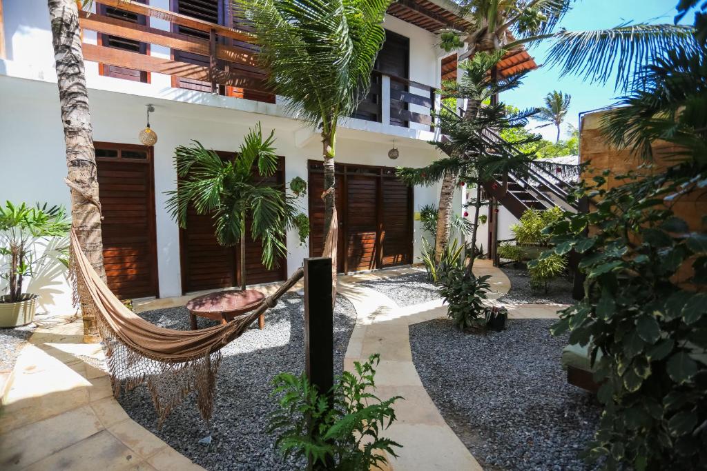 a hammock in front of a house with palm trees at Mandala Hostel Jeri in Jericoacoara