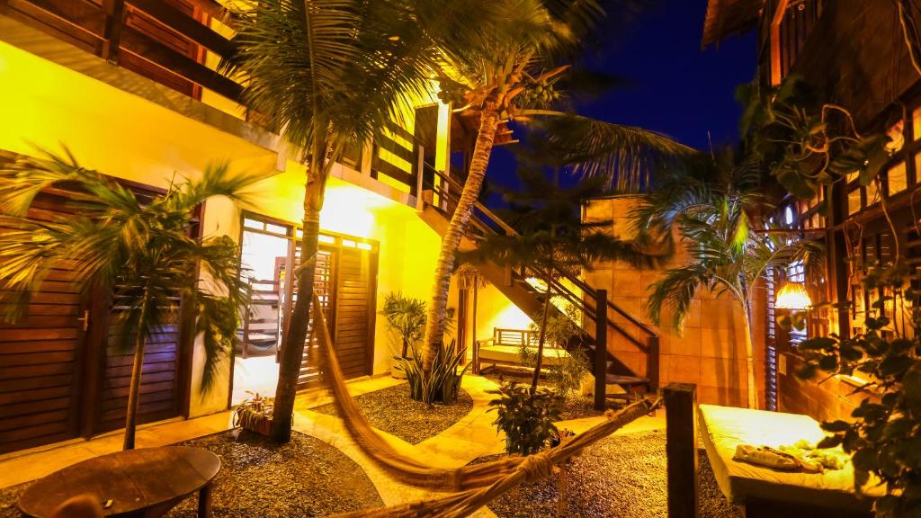 a courtyard with palm trees and a hammock at Mandala Hostel Jeri in Jericoacoara