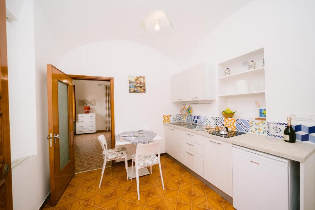 a kitchen with white cabinets and a table and chairs at Nonna Titti in Amalfi