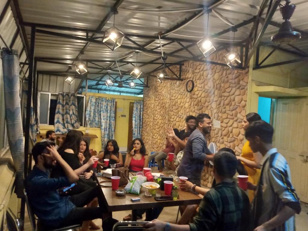 een groep mensen die rond een tafel in een kamer zitten bij Bubble Beds in Calcutta