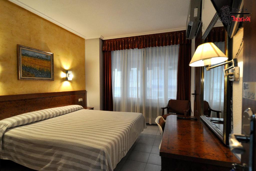 a hotel room with a bed and a desk and a window at Hotel Aragón in Salamanca