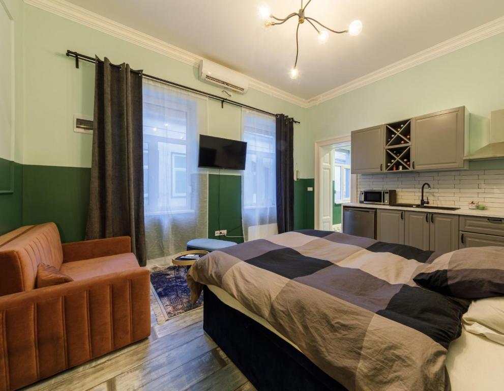 a bedroom with a bed and a chair and a kitchen at Cozy modern space at the heart of the city in Debrecen