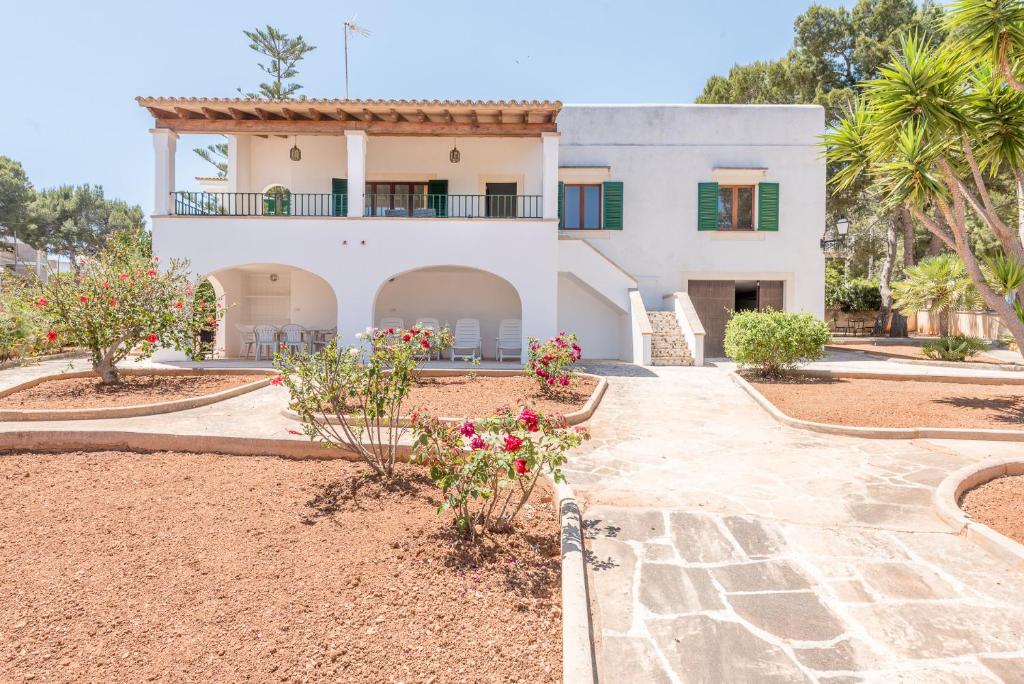 a large white house with a courtyard with flowers at Casa Ca'n Munar in Portocolom