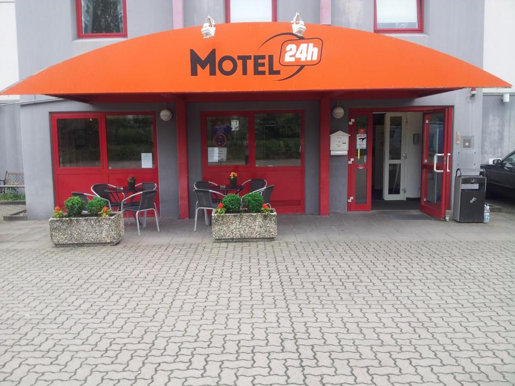 un motel con techo naranja, mesas y sillas en Motel 24h Hannover, en Hannover